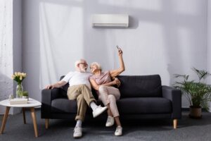 senior-couple-sits-on-sofa-changes-temp-of-mini-split-with-remote
